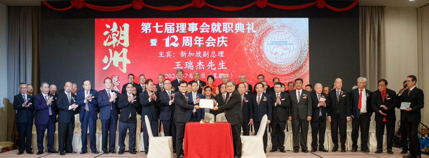 Group of people in suits with a certificate on a stage with a large screen.